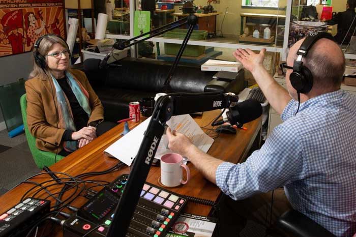 Kornbluth, left sits inside a studio being interviewed by Daniel Braunstein