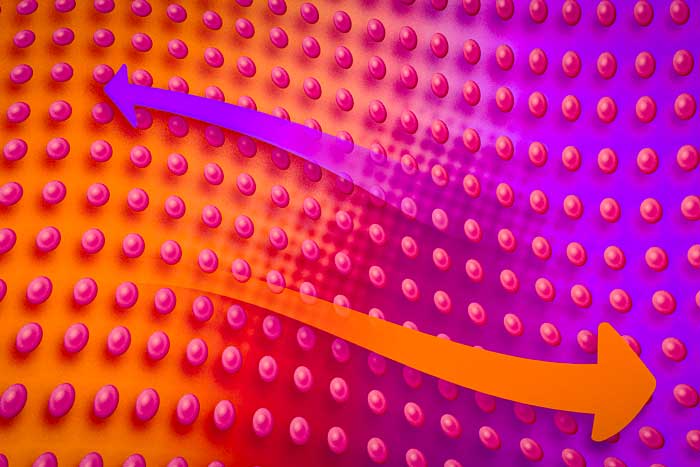 A wavey array of pink spheres floats like on water. A wavey orange arrow points to the right, and a wavey purple arrow points to the left.