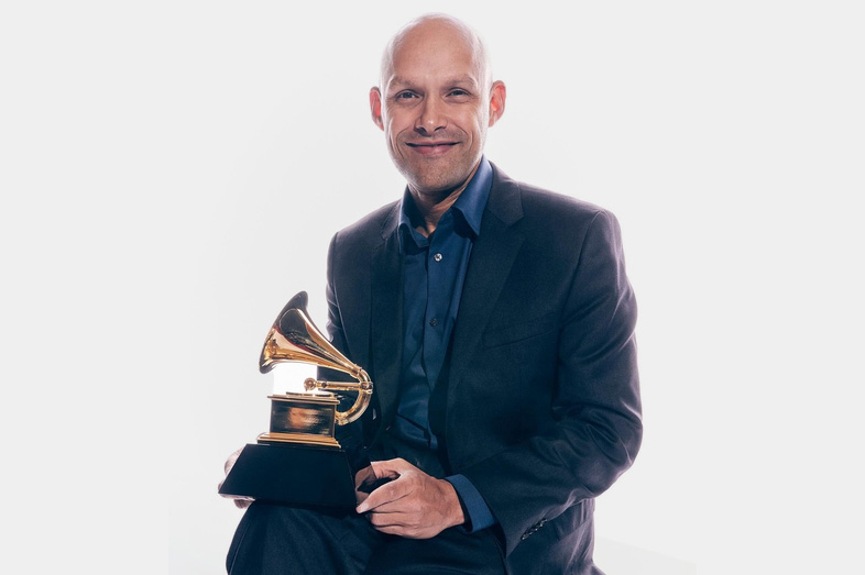 Miguel Zenón seated with Grammy award, which resembles a gramophone